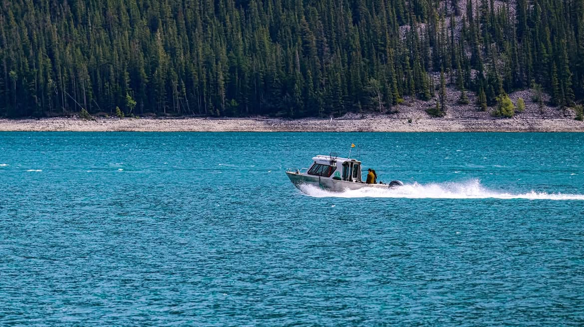 Motorboat crossing the turquoise water of Lake Minnewanka near Banff