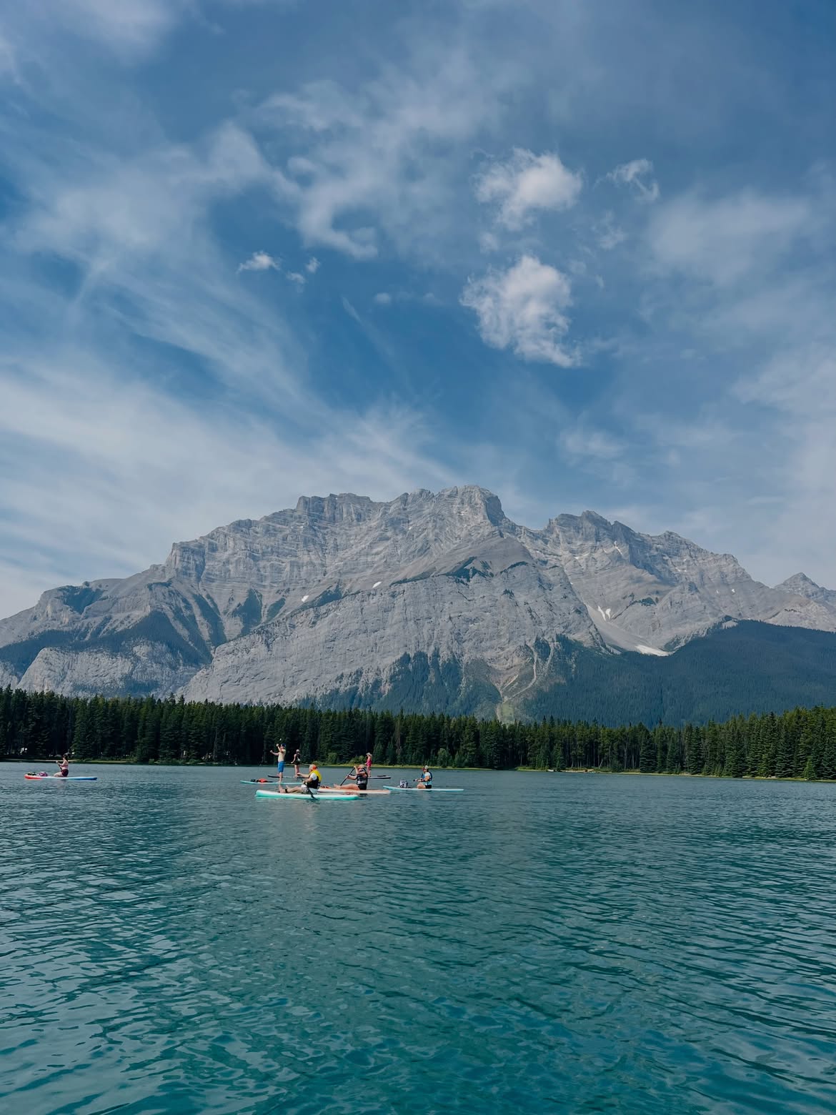 Paddleboarders on Two Jack Lake with a snow-capped mountain peak behind them