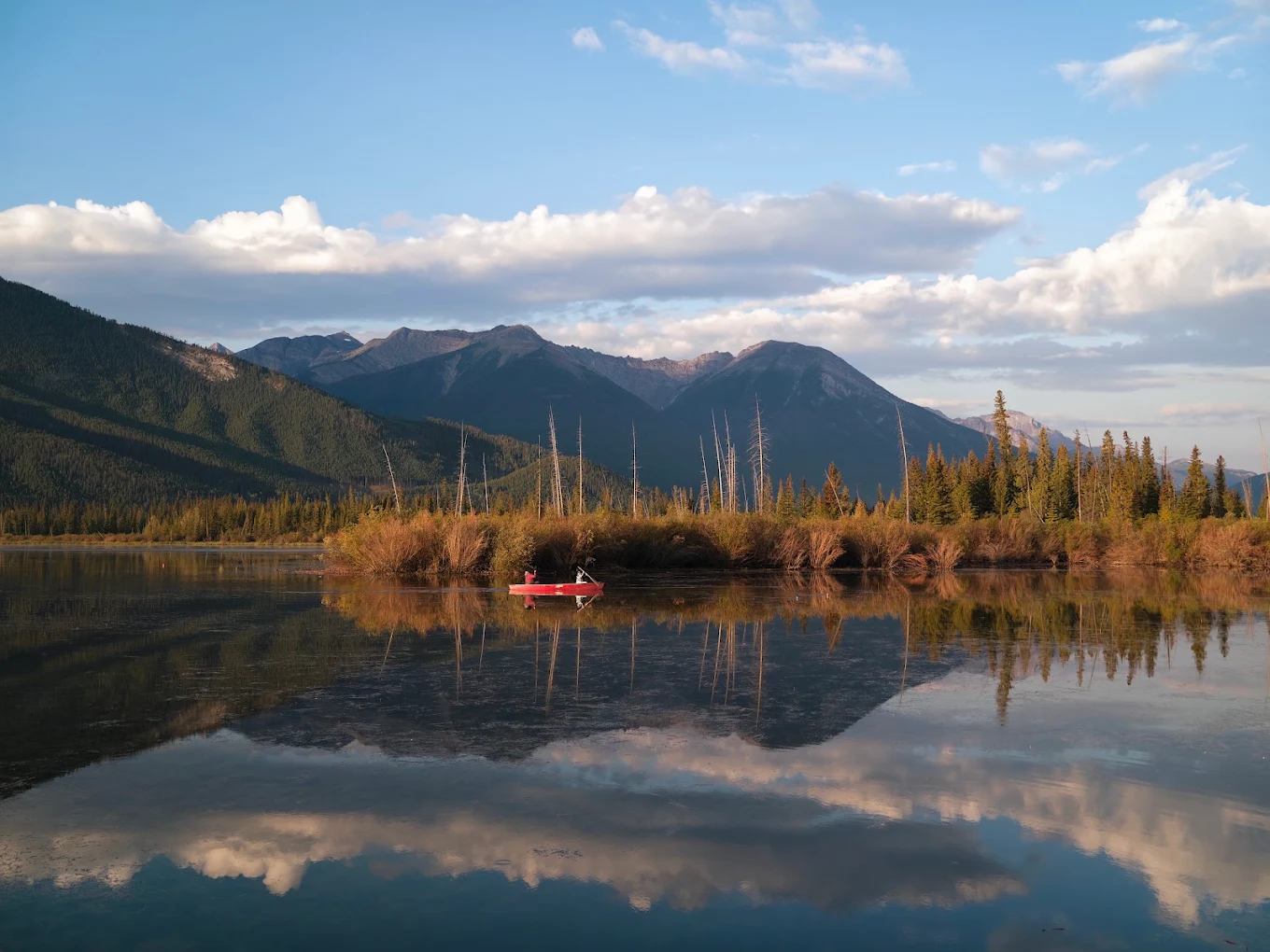 Canoe on the still water of Vermilion Lakes among wetland grasses at golden hour