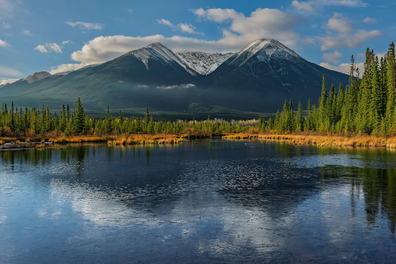 Fall colours and snow-dusted mountains reflected in Vermilion Lakes