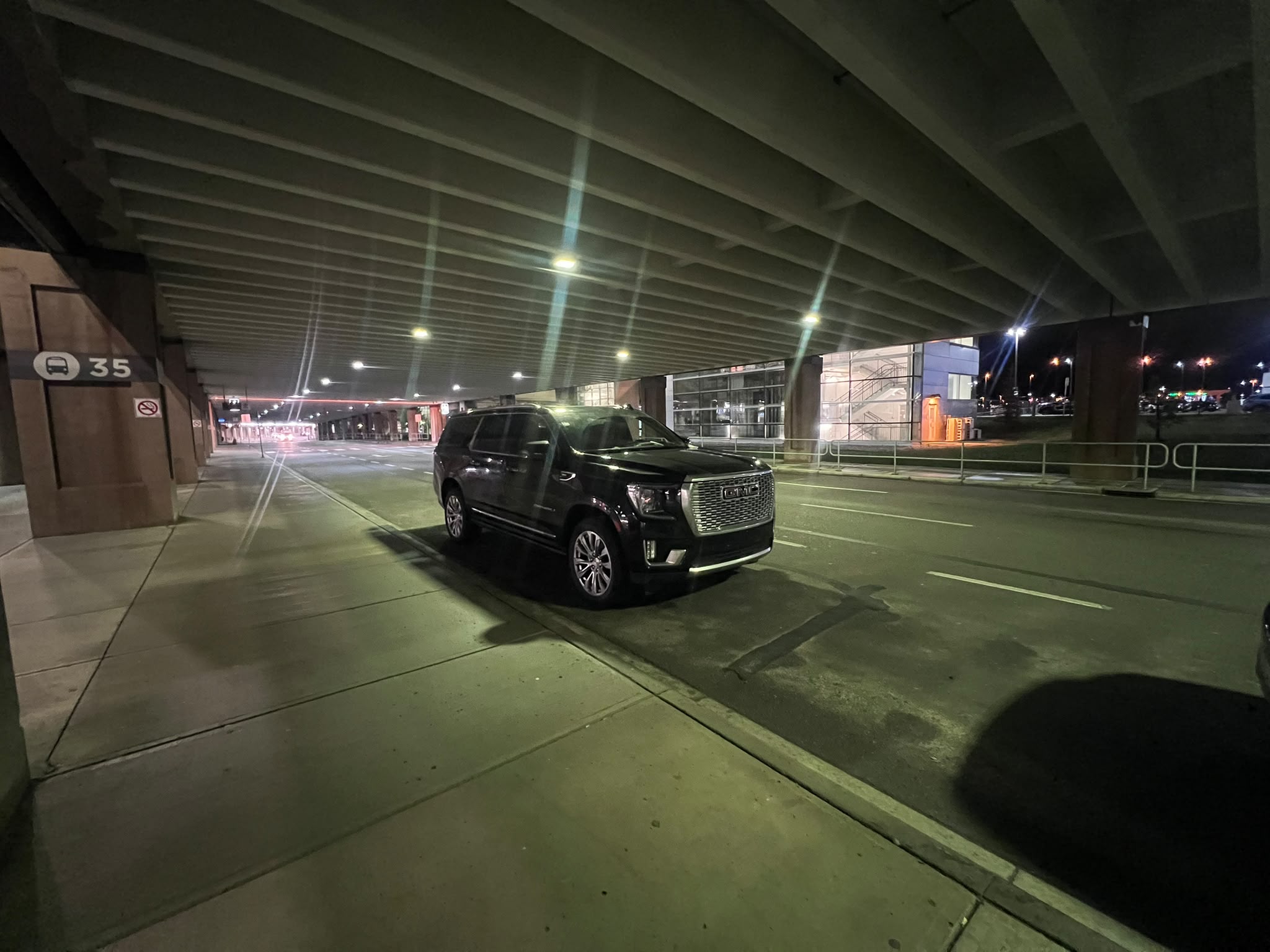 Black GMC Yukon XL Denali waiting at the Calgary Airport terminal curbside on a late-night arrival