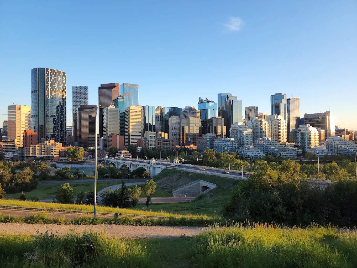 Downtown Calgary skyline above a bridge and the surrounding roads on a clear summer evening