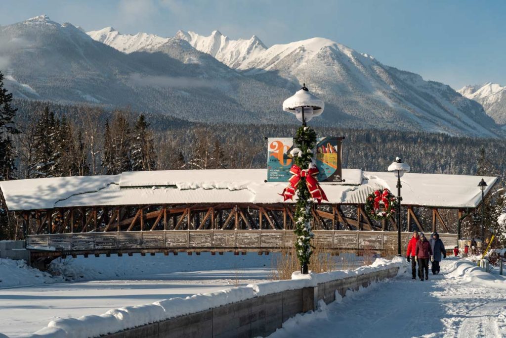 The covered Kicking Horse Pedestrian Bridge in Golden, BC under fresh snow, with winter mountains behind