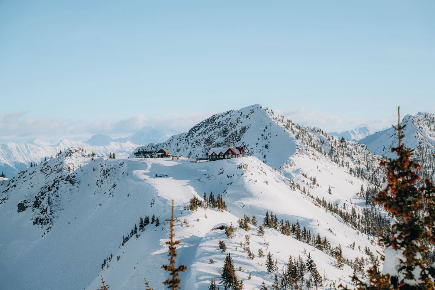 Snow-covered summit ridge and mountain lodge at Kicking Horse Mountain Resort above Golden, BC on a clear winter day