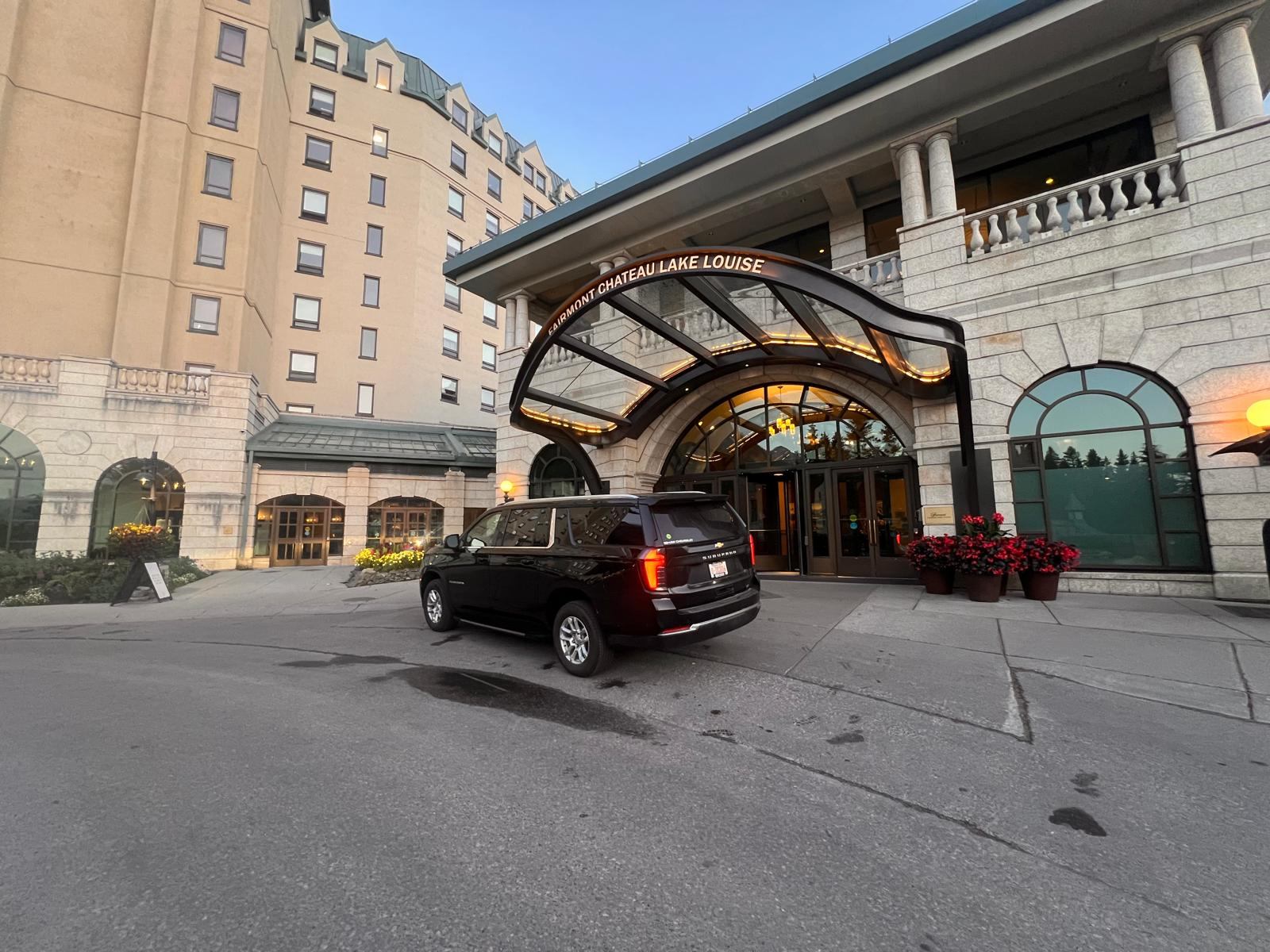 Black SUV at the Fairmont Chateau Lake Louise main entrance canopy at sunrise