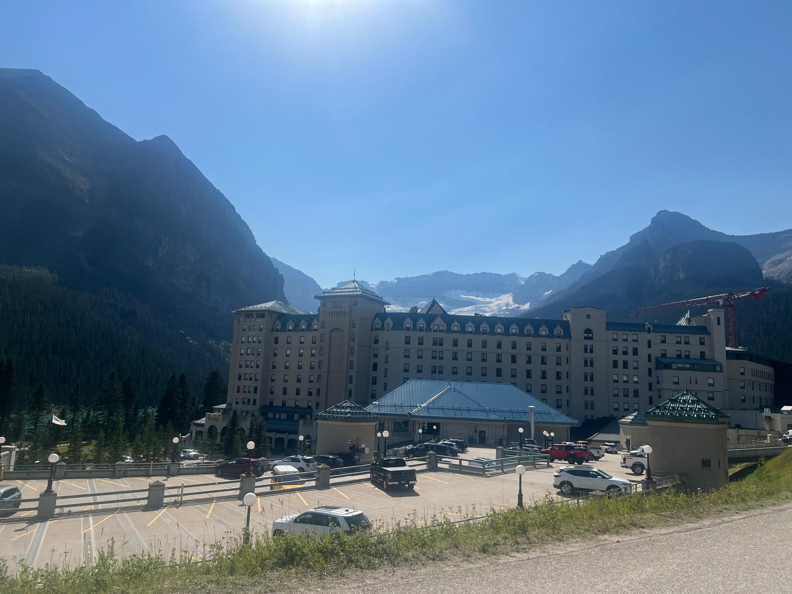 Fairmont Chateau Lake Louise below steep mountains and Victoria Glacier on a clear summer day