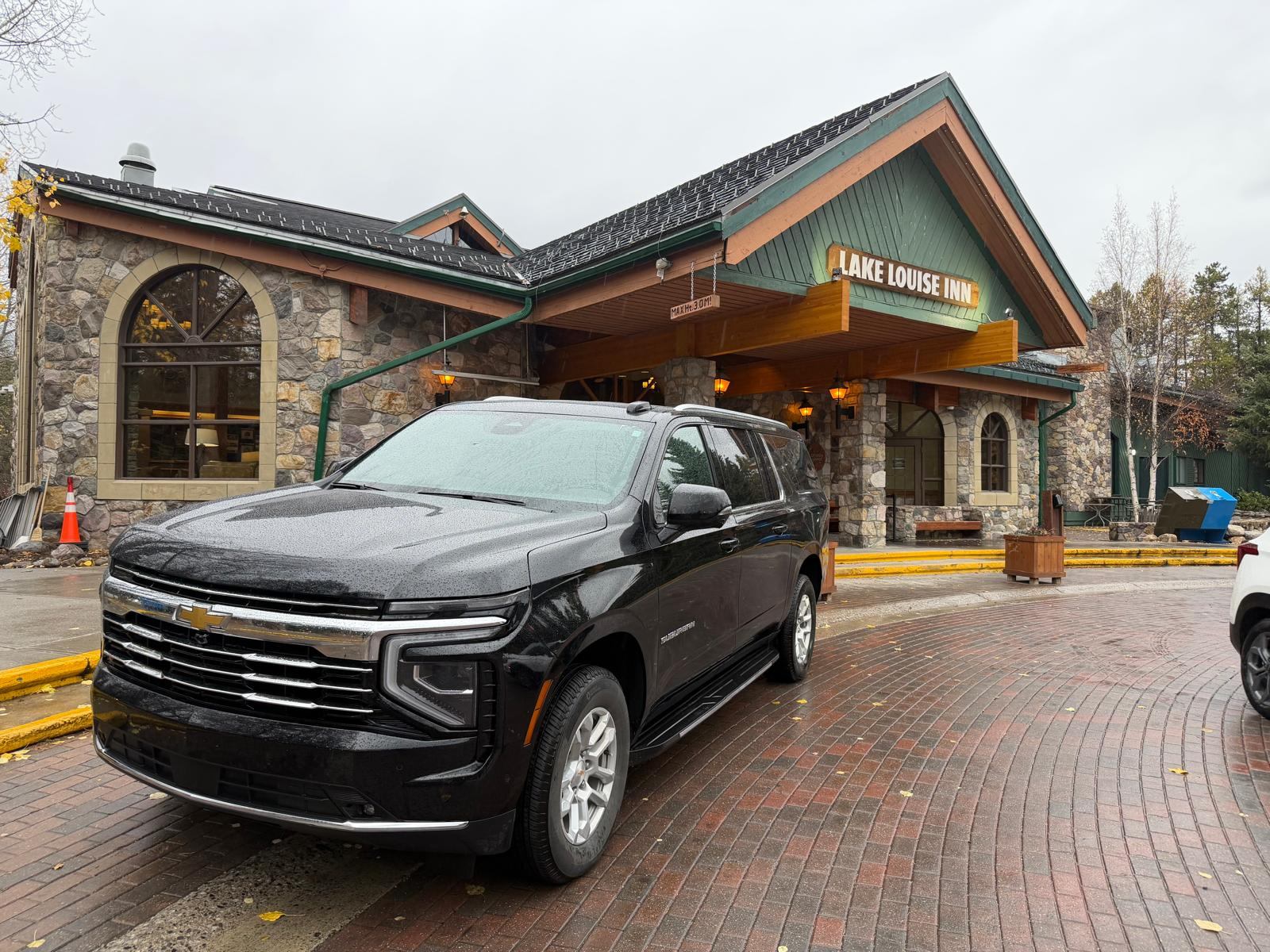 Red Mile Limousine Services black Chevrolet Suburban parked at the Lake Louise Inn entrance in Lake Louise village