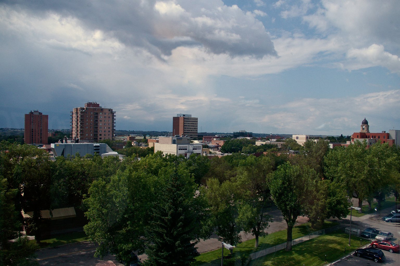 Downtown Lethbridge skyline above tree-lined streets on a summer day